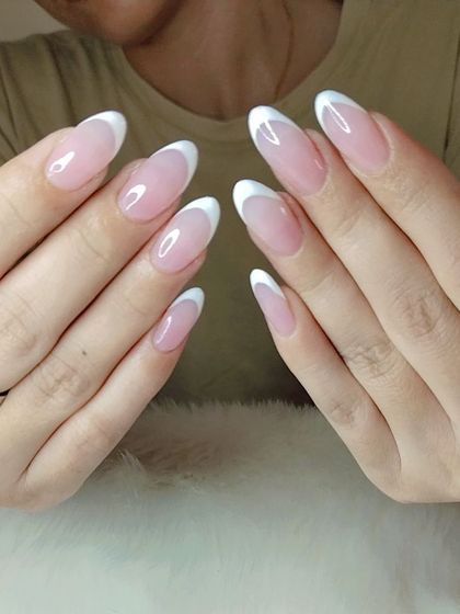 A classic French manicure on elegant, oval-shaped extensions. The clean white tips and natural pink base create a timeless and polished look that's perfect for any occasion.