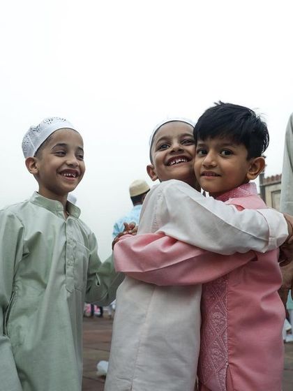 Children embrace in a moment of pure joy during Eid celebrations, a candid shot capturing the spirit of community and togetherness.