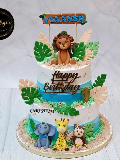 A wild 3kg two-tier jungle-themed cake for a first birthday. This chocolate cake is decorated with fondant animals and lush green leaves.