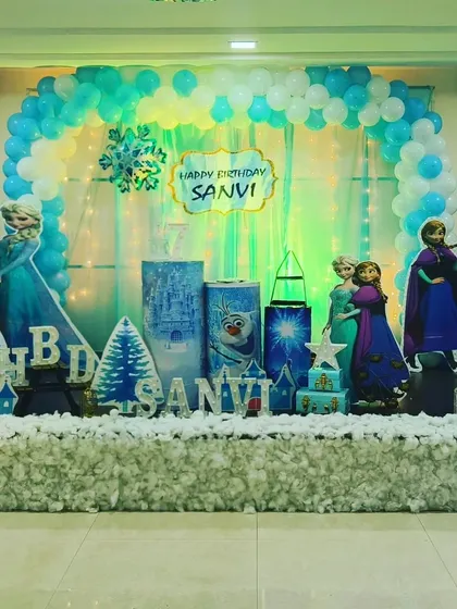 A grand Frozen-themed stage with faux snow, character cutouts, and a balloon arch, creating a truly immersive winter wonderland.