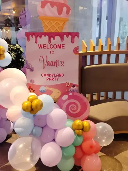 The entrance to the "Candyland Party," featuring a welcome sign with an ice cream cone graphic and a pastel balloon garland.