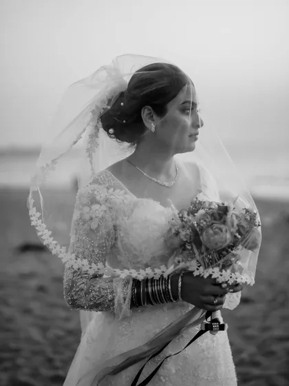 A stunning black and white portrait of the bride on the beach, her veil catching the wind.