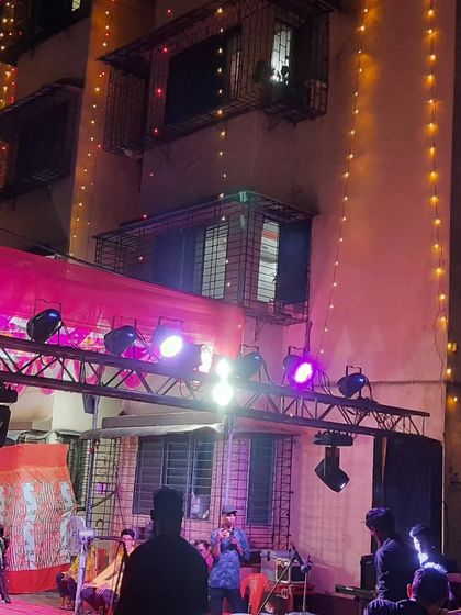 A lighting truss with PAR cans set up to illuminate a stage for a nighttime event in a residential society.