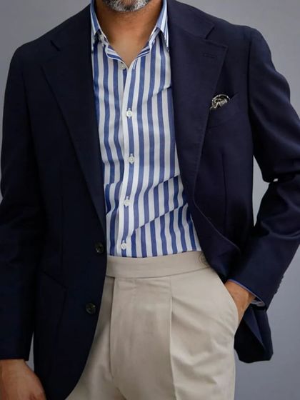 A classic combination: a navy blazer paired with a striped shirt and beige trousers. Each piece is tailored to work together, creating a cohesive and stylish outfit.