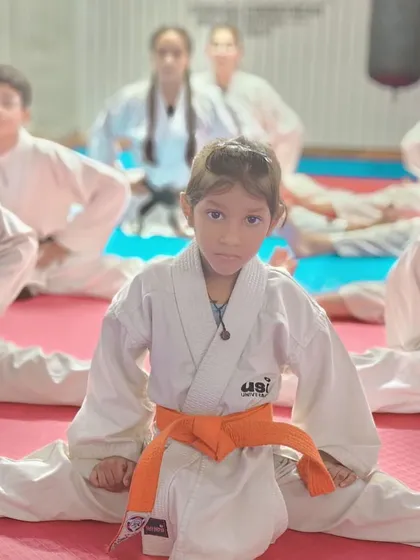A young student demonstrates excellent flexibility and focus while performing a split during a training session.