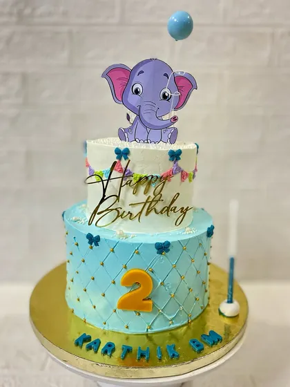 A beautiful two-tier butterscotch cake with a cute elephant topper for a second birthday.