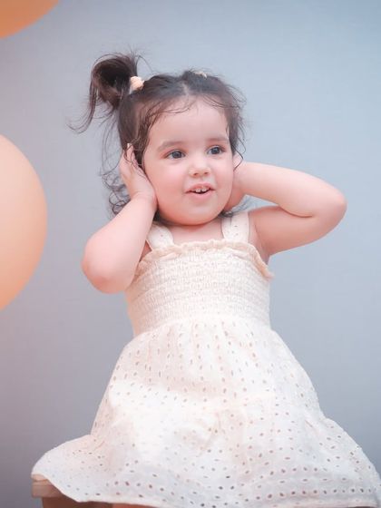 The soft lighting and pastel balloons create a dreamy atmosphere for this toddler's second birthday photoshoot.
