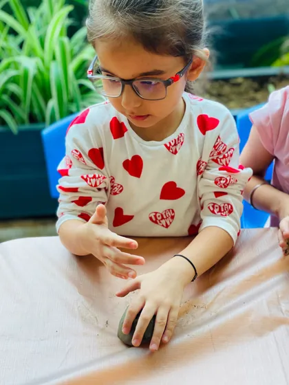 Every child approaches the task with their own unique technique. Here, a student carefully presses and shapes the clay for her Ganesha idol.