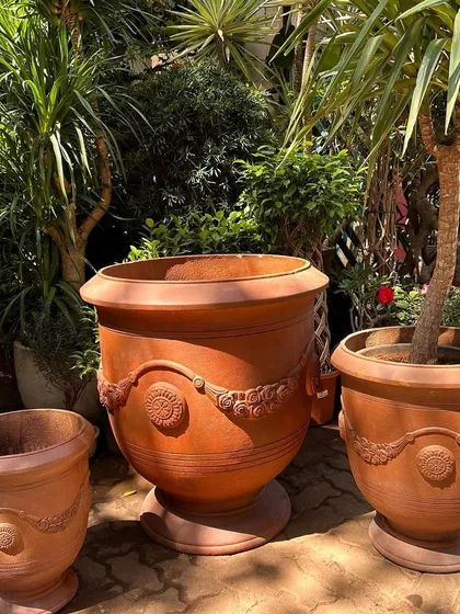 This is a new collection of large, Roman-style terracotta planters. The classic shape and decorative garland details add a touch of vintage European elegance to a garden or patio space.