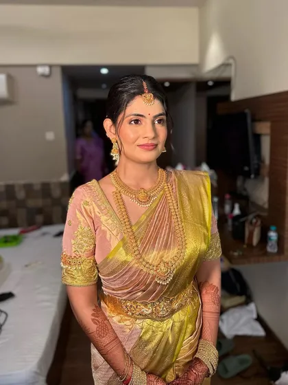 A beautiful South Indian bride with her hair in a neat bun, ready for the traditional floral braid. The makeup is kept classic and radiant to match the elegance of the look.