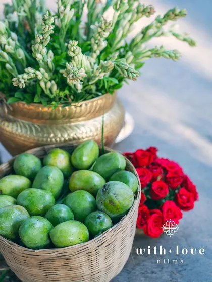 A basket of fresh green mangoes and a brass pot of tuberose, elements used to create a sensory experience at a summer wedding.