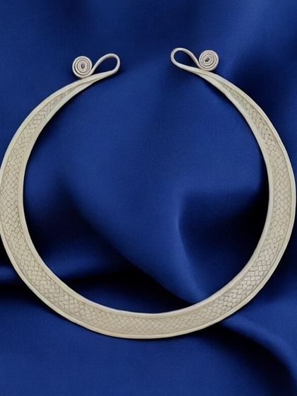 A premium pure silver husli, or rigid collar necklace. This minimalist piece has a subtle texture and coiled ends, perfect for a sleek, modern ethnic look.
