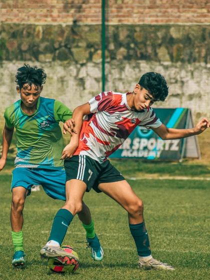 Two older players are locked in a physical battle for the ball, showcasing strength and technique.