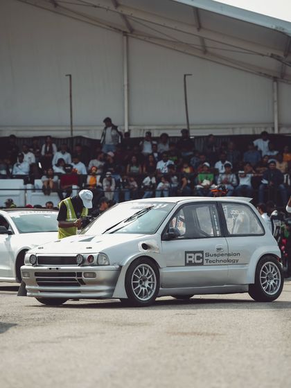 A classic silver Honda City, modified for the track, waits for its turn to race, proving that even older models can be transformed into competitive drag machines.