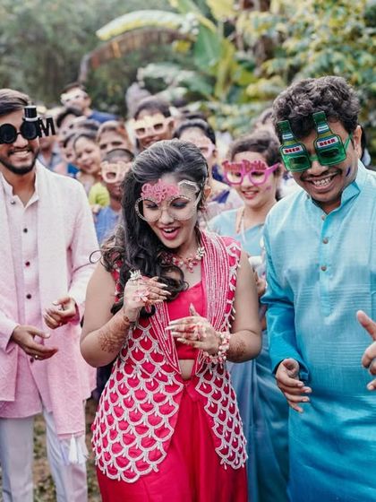 The couple and their guests dancing with fun props, capturing the carefree spirit of the Haldi party.