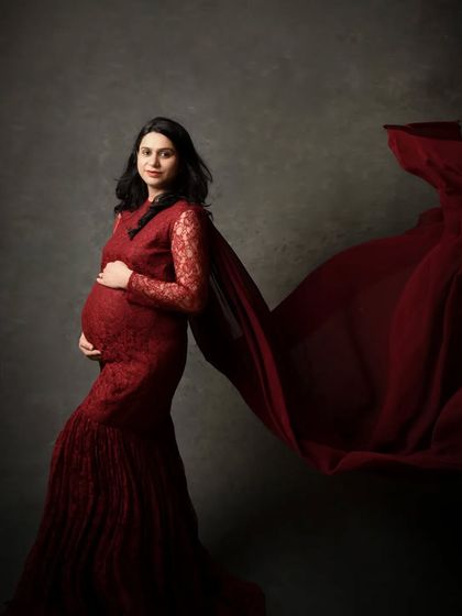 The deep red lace gown combined with a fabric toss creates a portrait that is both romantic and powerful. The dark background makes the color truly pop.
