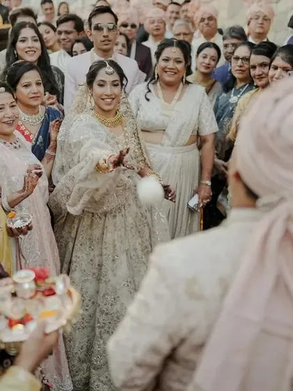 A traditional moment where the bride playfully throws rice at the groom, captured amidst a crowd of smiling family members.