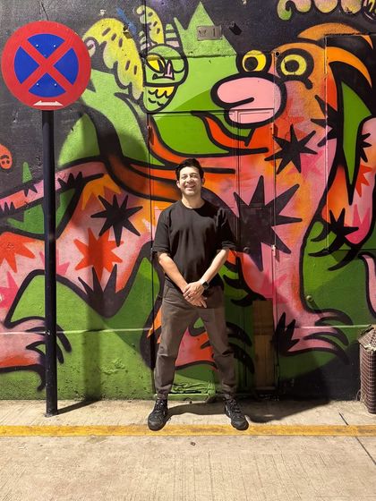 Posing against a vibrant mural. This reflects my love for urban art and culture, which often inspires my creative work.