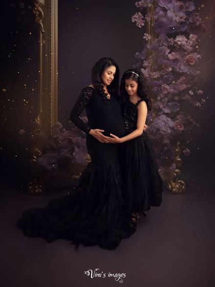 A loving embrace. The older sister holds her mother's bump, sharing a quiet moment of connection with her soon-to-be sibling in this elegant, dark-toned portrait.