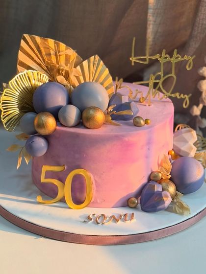 Turning 50 never looked so elegant. This cake features a textured lilac base, edible gold accents, and modern floral arrangements to match the grace and glow of a golden celebration.