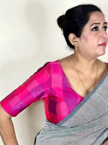 Our Pink Checks Blouse is a blend of tradition and trend. Here it's paired with a simple grey saree, allowing the vibrant pink to truly pop.