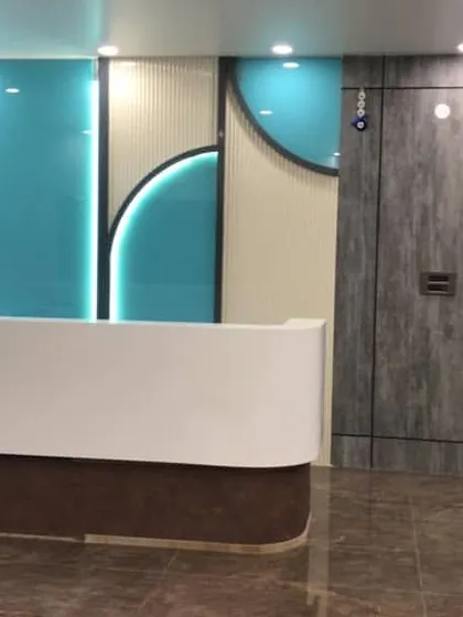 The completed reception desk at a school project. The design uses clean lines, a minimal white counter, and vibrant, back-lit turquoise panels to reflect the institution's modern values and create a positive and inviting atmosphere for students and visitors.