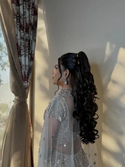 The silhouette of her sangeet hairstyle, a high ponytail with cascading curls, perfect for movement and style.