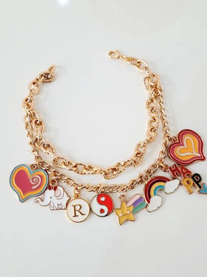 A vibrant, fully loaded custom charm bracelet I made for a client. It features a mix of colorful hearts, a happy elephant, a yin-yang symbol, a rainbow, and the initial 'R' to make it extra personal.