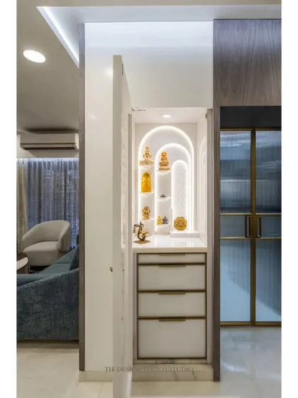 The mandir door opens to reveal a serene, backlit space with arched niches for idols and drawers for storing pooja essentials. It's a perfect blend of beauty and functionality.