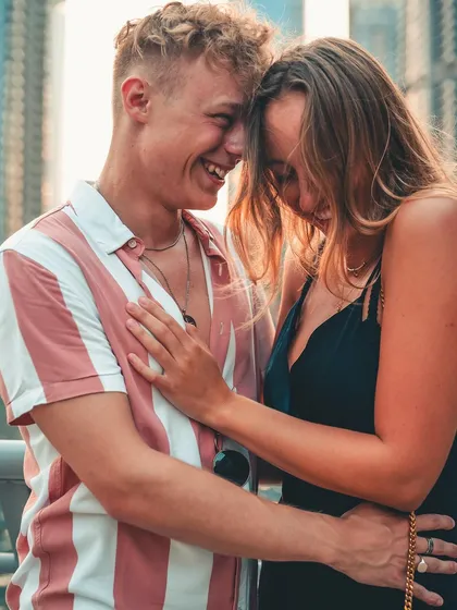 A duplicate of image 103, a close-up of a couple sharing a laugh, with the blurred city in the background.