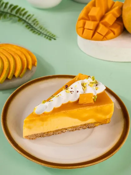 A perfect slice of mango cheesecake on a rustic plate. This shot focuses on the creamy texture and the beautiful contrast between the golden mango puree and the biscuit base.