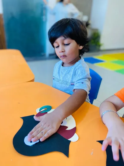 A close-up of a student's hands as he pats down a piece of his craft, showing his engagement in the tactile process.