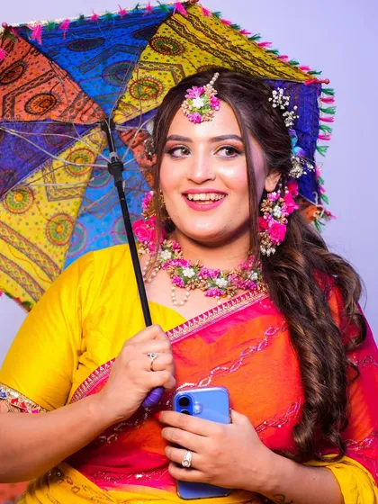 Having fun at her Mehendi ceremony. The colorful umbrella adds a playful touch to her overall look.