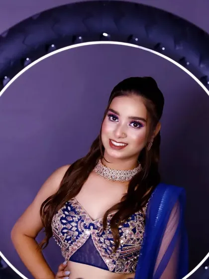 A modern studio portrait showcasing our use of professional lighting. The model, framed by a ring light, is wearing an intricate blue lehenga, highlighting our ability to create crisp, contemporary beauty shots for model portfolios.