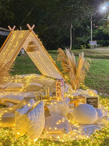 A cozy and bohemian-style picnic or proposal setup. I used a small tent, lots of cushions, and a blanket of fairy lights on the grass to create an intimate and dreamy outdoor setting.