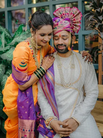 A sweet, candid moment between the couple. The bride's intricate gold jewelry and the groom's pearl necklace are highlighted in this close-up shot.