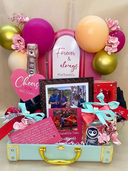 Celebrating love stories is one of my greatest joys. This custom trunk was designed for a special couple, complete with personalized photos, celebratory champagne, and a balloon arch to mark their 'Forever & Always' moment.