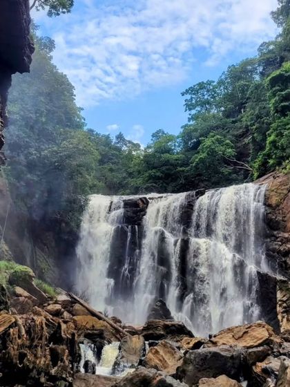 The powerful cascade of Sathodi Falls, seen through the rocks. It's a perfect spot for nature photography.