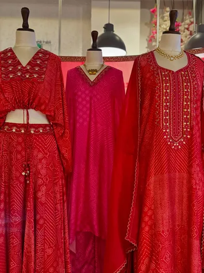 This display shows the variety within the red bandhani theme, from a tie-front crop top to a flowing kaftan and a classic kurta.