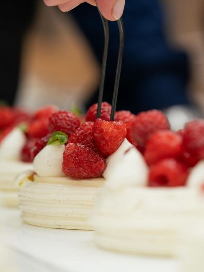 Chef Bachour's delicate touch, placing fresh raspberries on a perfect pavlova.