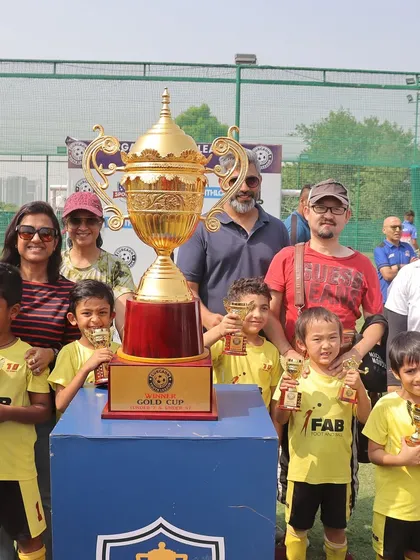 The team with their parents and a giant trophy. The journey of a football player is marked by growth, wins, and an ever-evolving trajectory.