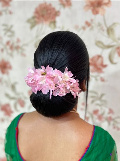 A clear, centered shot of the perfect, sleek bun with pink flowers.