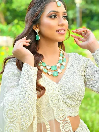 A beautiful portrait highlighting the intricate embroidery of our all-white lehenga, paired perfectly with contrasting green jewelry.