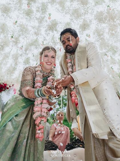 The couple showers each other with rice during their ceremony, a moment of fun and blessing under a canopy of flowers.