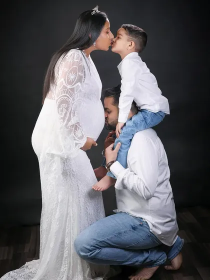 A sweet moment where the older brother kisses his mom's belly, and dad kisses his son, a chain of family love.