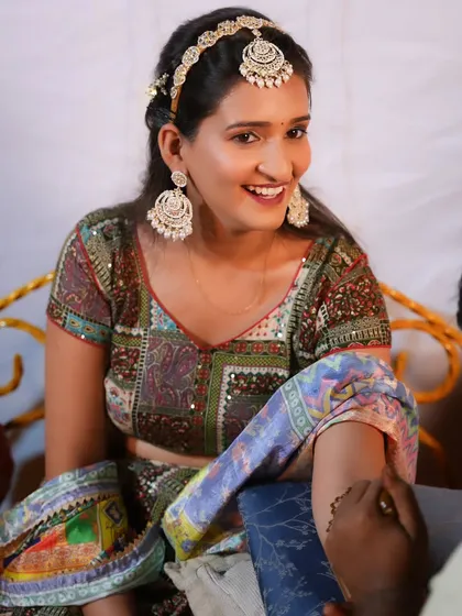 A candid moment from a Mehendi ceremony, with the bride's makeup looking soft and natural.