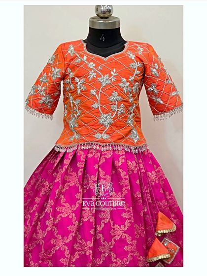 A modern take on the Pattu Pavadai with this orange and pink set. The blouse features three-quarter sleeves with stunning silver threadwork.