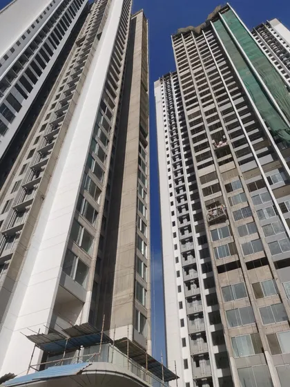 A low-angle shot of the Sunteck City towers under construction. This view highlights the scale of the project and the progress of the facade work, with large window openings designed for maximum natural light and ventilation.