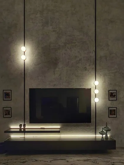 Details matter. Here, we used a combination of ambient and accent lighting to transform a simple TV unit into a dramatic focal point, highlighting the texture of the concrete wall and creating a moody, sophisticated atmosphere.