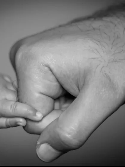 A powerful black and white close-up of a newborn's tiny hand wrapped around their father's finger. It's these small, delicate details that tell the biggest stories of love and connection.